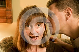 Man whispering in ear of woman