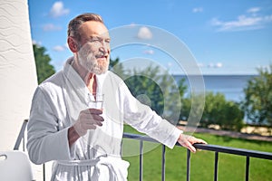 Man in a white bathrobe standing on the balcony