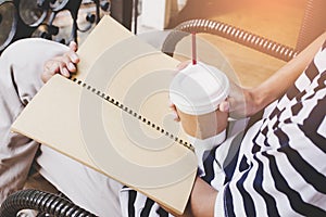 Man in white and black shirt,Holding cup of coffee sitting on chair ,Reading book ,Copy space for your text