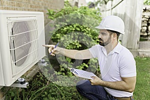 man with a white hard hat holding a clipboard, inspect house thermopump