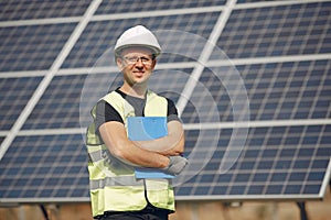 Man in a white helmet near a solar panel