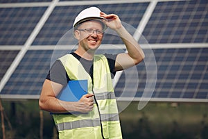 Man in a white helmet near a solar panel