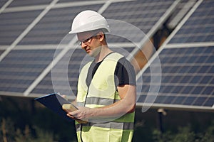 Man in a white helmet near a solar panel