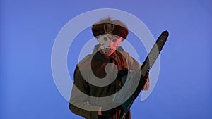 Man in white mask with chainsaw in hands on blue background with red neon light. Image of maniac Jason Voorhees from