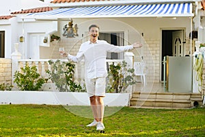 A man in white meets his guests against the backdrop of his large house. Purchase of real estate, travel, rent. Guy drinks wine on