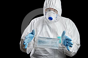 Man in white protective suit and facepiece respirator with medical face masks in hands