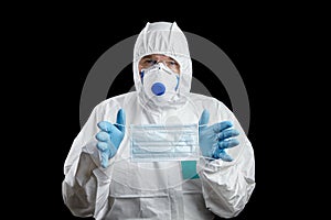 Man in white protective suit and facepiece respirator with medical face masks in hands