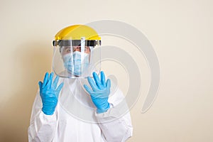 Man in white protective suit and goggles and surgical gloves to avoid getting coronavirus copy space