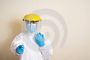 Man in white protective suit and goggles and surgical gloves to avoid getting coronavirus copy space