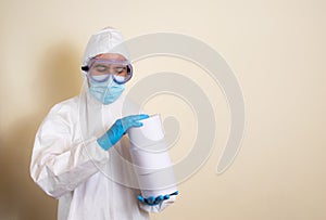 Man in white protective suit and goggles and surgical gloves with toilet paper in his hands to avoid getting coronavirus copy