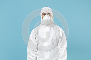 Man in white protective suit respirator mask isolated on blue background studio. Epidemic pandemic new rapidly spreading