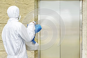 Man in a white protective suit spraying disinfectant in the office building