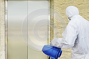 Man in a white protective suit spraying disinfectant in the office building