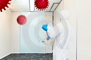 Man in a white protective suit spraying disinfectant in the office room