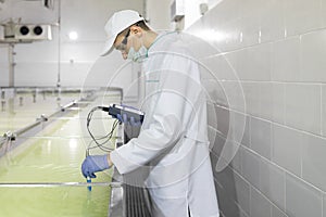 Man in a white robe and a cap make an inspection of dairy products