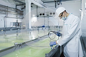Man in a white robe and a cap make an inspection of dairy products