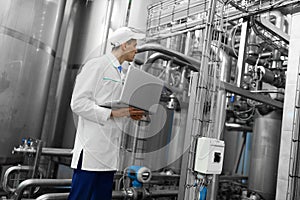 Man in a white robe with a laptop in his hands among the chrome pipes