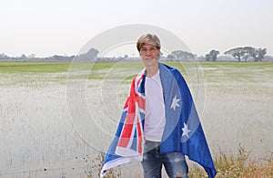 The man in white shirt with Australia flag on his shoulder on nature view background