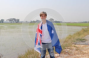 The man in white shirt with Australia flag on his shoulder on nature view background