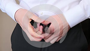 Man in white shirt buckling the belt on his pants