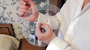 Man in white shirt fastens cufflinks