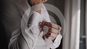 Man in a white shirt fastens his cufflinks