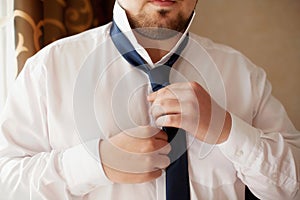 Man in white shirt fixing his black tie, closeup