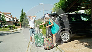 Man in white shirt grabs his head in frustration when wife brings more baggage.