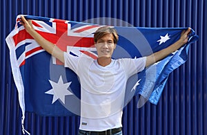 The man in white shirt is holding Australia flag in his hands and raising to the end of the arm