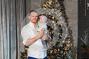 A man in a white shirt holds a six-month-old baby girl in his arms