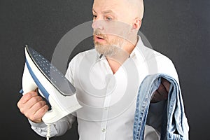 Man in a white shirt with an Ironing Flatiron and jeans in his hands