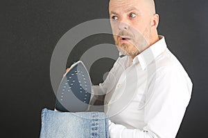 Man in a white shirt with an Ironing Flatiron and jeans in his hands