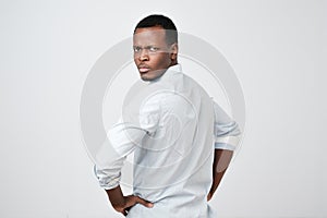 Man in white shirt looking behind at camera over his shoulder showing critical attitude.