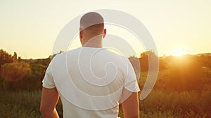 Man in white shirt looking at sunset. Back view with natural landscape. Contemplation and solitude concept. Design for