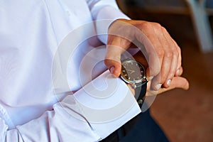 Man in a white shirt looks at his watch