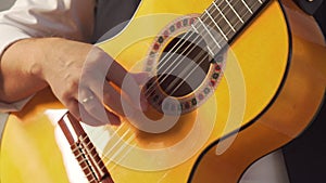 Man in a white shirt plays a classical guitar close-up