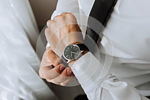 a man in a white shirt puts a watch on his hand, close-up