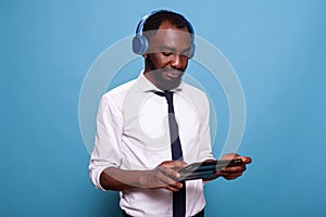 Man in white shirt relaxing with wireless headphones looking at online show on tablet computer