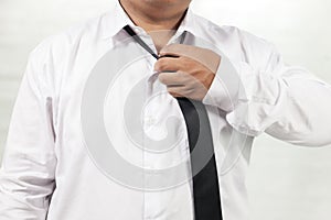 Man in white shirt taking off neck tie