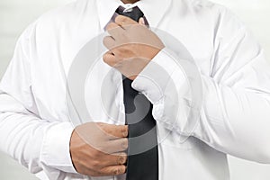 Man in white shirt taking off neck tie