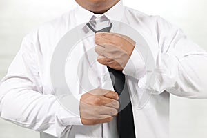 Man in white shirt taking off neck tie