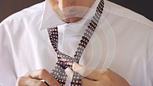 Man in white shirt tying a tie. Close up