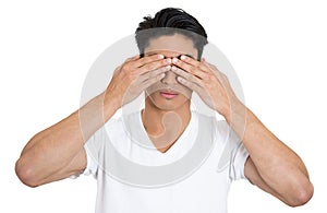 Man in white t-shirt covering his eyes with hands over white background