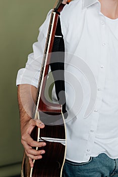 a man in a white T-shirt holds an acoustic guitar in his hands