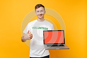 Man in white t-shirt written inscription green title volunteer hold laptop pc computer with blank empty screen isolated
