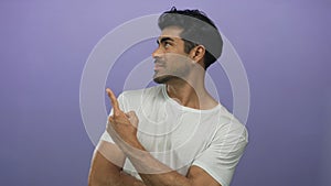 Man in white tee shirt pointing finger at side while looking offframe in a purple studio setting; curiosity