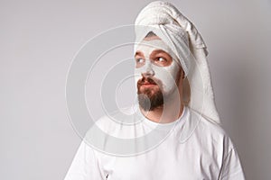 Man in white tshirt apply facial mask stand against white background. Beauty treatment, grooming and wellbeing concept