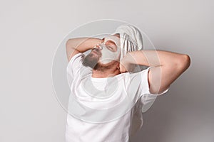 Man in white tshirt apply facial mask stand against white background. Self care morning spa procedure