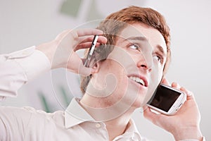 Man in white with two mobile phones