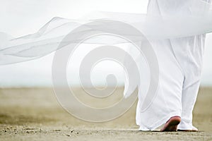 Man in white walking on sand